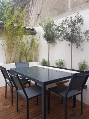 a glass table and chairs on a patio with trees at Maison vue Cité 2 in Carcassonne