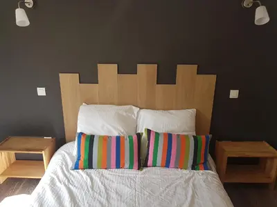 a bed with a wooden headboard and two pillows at Maison vue Cité 2 in Carcassonne