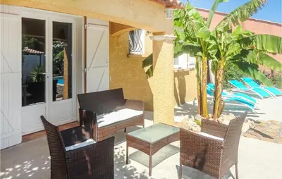 a patio with chairs and a table and a palm tree at Cozy Home In Salles D'aude With Wifi in Salles-d'Aude