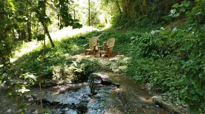 two benches sitting on a hill next to a stream at Gîte Terra Bosca in Cambounès