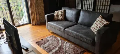 a black couch in a living room with a rug at Diamond - Gîte dans vieux prieuré près de Carcassonne in Sainte-Eulalie