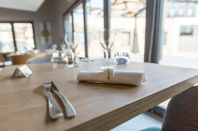 a wooden table with wine glasses and a napkin at Hôtel Mets et Plaisirs in Mazamet