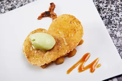 a white plate with a piece of food with ice cream on it at Hôtel Mets et Plaisirs in Mazamet