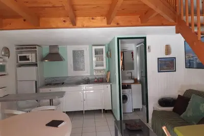 a living room with a table and a kitchen at Pavillon Grazel GRUISSAN in Gruissan