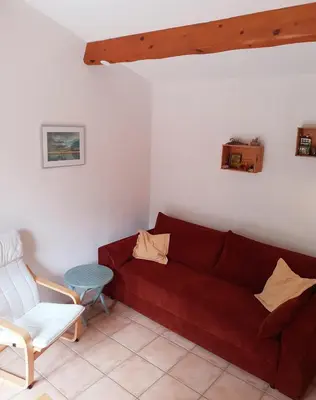 a living room with a red couch and a chair at Tiny House Belleraze in Saint-Jean-de-Minervois