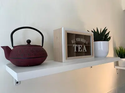 a shelf with a tea pot and a clock at Appartements Voltaire - Carcassonne Centre in Carcassonne