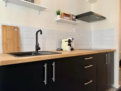 a kitchen with black cabinets and a sink at Appartements Voltaire - Carcassonne Centre in Carcassonne