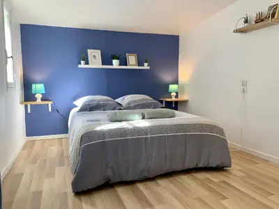 a bedroom with a bed with a blue wall at Appartements Voltaire - Carcassonne Centre in Carcassonne