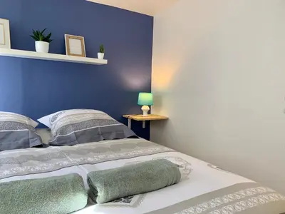 a bedroom with a bed with a blue wall at Appartements Voltaire - Carcassonne Centre in Carcassonne