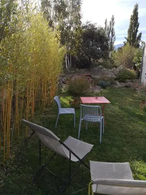 two chairs and a table in a yard at Chambre d'hotes CHEVREFEUILLE in Molitg les Bains