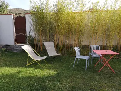 a group of chairs and a table in a yard at Chambre d'hotes CHEVREFEUILLE in Molitg les Bains