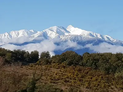 a snow covered mountain with clouds in front of it at Chambre d'hotes CHEVREFEUILLE in Molitg les Bains