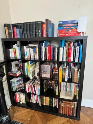 a black book shelf filled with books at La Maison d'hôtes du Chapelier in Espéraza