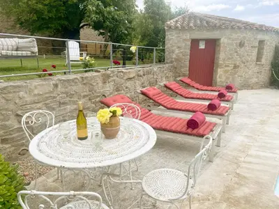 a group of chairs and a table with a bottle of wine at Les Oliviers in Cesseras