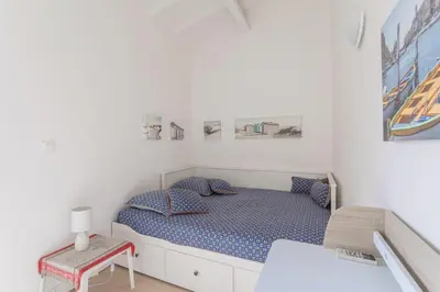 a small white bedroom with a bed and a table at Central Narbonne with rooftop terrace in Narbonne