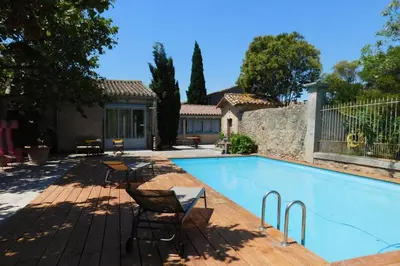 a swimming pool with chairs and a house at Loft atelier dans ancien domaine viticole in Moux