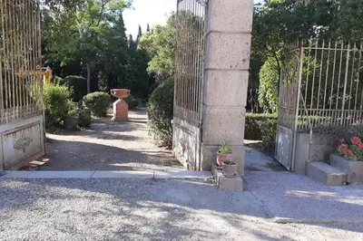 an entrance to a garden with a fence and flowers at Loft atelier dans ancien domaine viticole in Moux