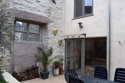 a building with a table and chairs in front of it at Havre de paix au pied de la montagne in Les Ilhes