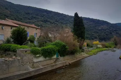 a bridge over a river next to a mountain at Havre de paix au pied de la montagne in Les Ilhes