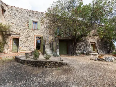 a stone house with a door and a yard at Charming Holiday Home in Tautavel with Balcony in Tautavel
