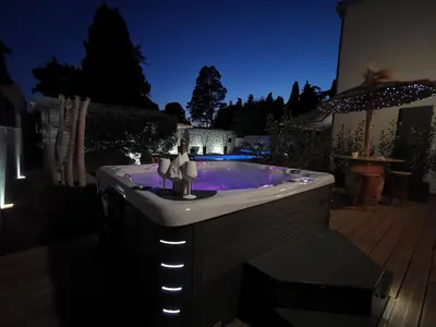 a jacuzzi tub in a backyard at night at Suite l'inattendu avec Spa privatif et espace bien-être. in Moussan