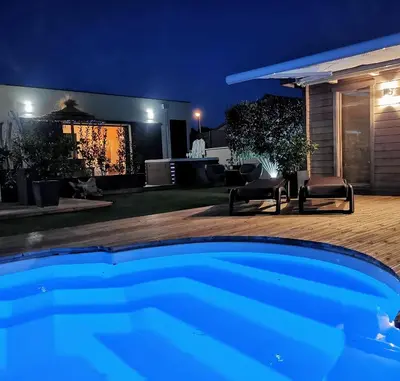 a backyard at night with a swimming pool at Suite l'inattendu avec Spa privatif et espace bien-être. in Moussan
