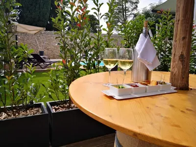 two glasses of white wine on a wooden table at Suite l'inattendu avec Spa privatif et espace bien-être. in Moussan