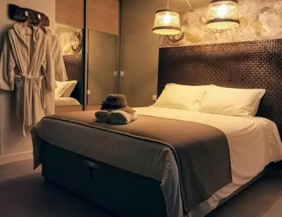 a bedroom with a large bed and a robe at Suite l'inattendu avec Spa privatif et espace bien-être. in Moussan