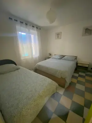 a bedroom with two beds and a checkered floor at la Porte bleue in Capestang