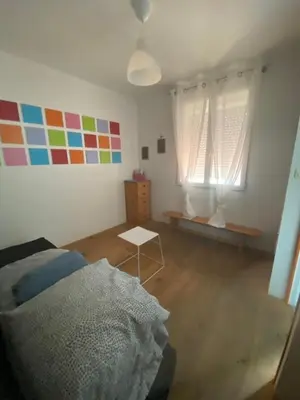 a bedroom with a bed and a table and two windows at la Porte bleue in Capestang