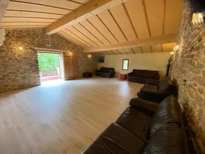 a living room with a couch and a stone wall at La Grange du Soleil in Rouvenac