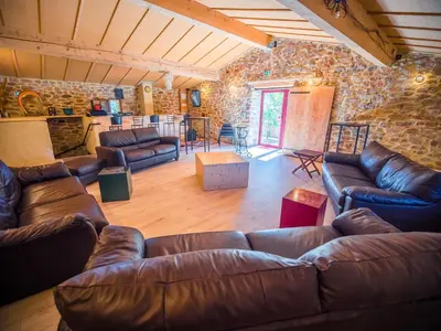 a living room with leather furniture and a stone wall at La Grange du Soleil in Rouvenac