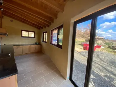 a kitchen with a large sliding glass door at La Grange du Soleil in Rouvenac
