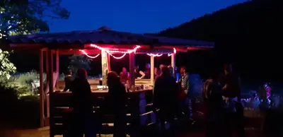 a group of people sitting at a bar at night at La Grange du Soleil in Rouvenac