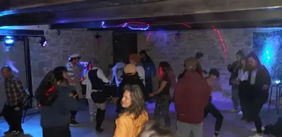 a group of people dancing in a room with lights at La Grange du Soleil in Rouvenac