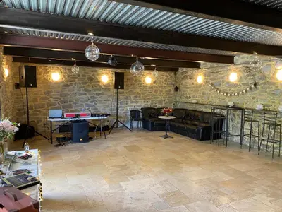 a large room with a stone wall and tables and lights at La Grange du Soleil in Rouvenac