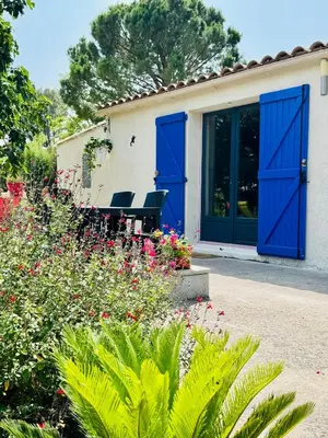 a house with blue doors and a garden with flowers at Mas des Tournevents in Lézignan-Corbières