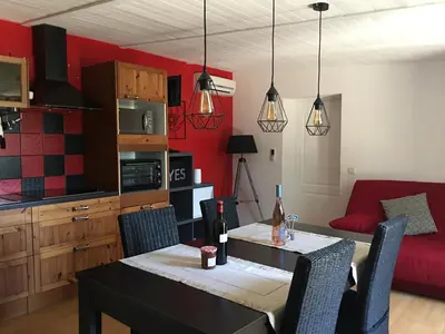 a living room with a table and a red couch at Mas des Tournevents in Lézignan-Corbières