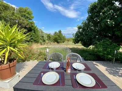 a picnic table with plates and a bottle of beer at Mas des Tournevents in Lézignan-Corbières
