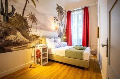 a bedroom with a bed and a window with red curtains at Le Belem in Carcassonne
