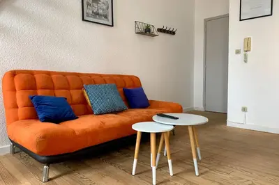 an orange couch with blue pillows and two tables at Duplex Carcassonne centre in Carcassonne