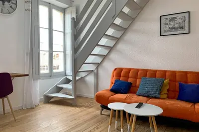 a living room with an orange couch and stairs at Duplex Carcassonne centre in Carcassonne