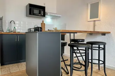 a kitchen with a bar with stools and a microwave at Duplex Carcassonne centre in Carcassonne