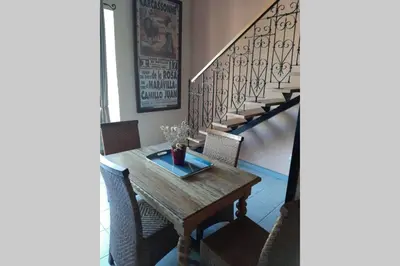 a dining room table with chairs and a staircase at Cave atelier dans ancien domaine viticole in Moux