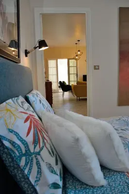 a bedroom with a bed with pillows and a living room at MAISON DIANA in Capestang