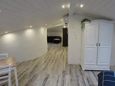 a living room with a wooden floor and a white door at Le Parc - Suite climatisée in Magrie