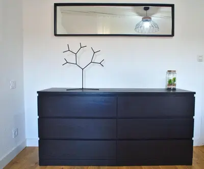 a black dresser with a tree on top of it at T3 cosy au centre de Castelnaudary in Castelnaudary