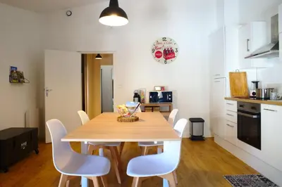 a kitchen with a wooden table and white chairs at T3 cosy au centre de Castelnaudary in Castelnaudary