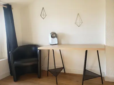 a black chair sitting next to a wooden desk at T3 cosy au centre de Castelnaudary in Castelnaudary