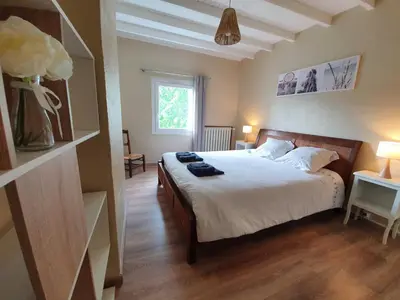 a bedroom with a bed with white sheets and a window at Gîte confortable avec SPA privé et confort moderne in Pont-de-Larn